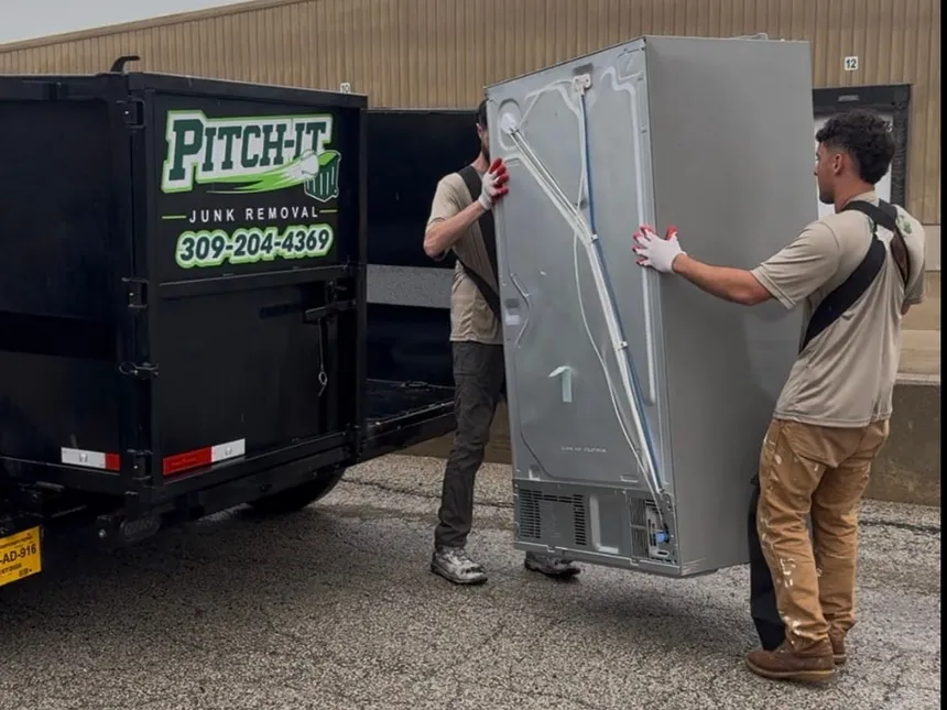 The Pitch It crew carrying a refrigerator to the dump trailer