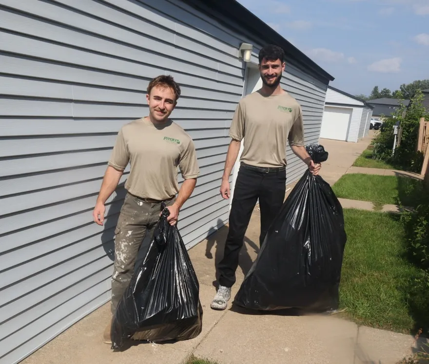 Rocco Geisz and Brady Moser, the owners of Pitch It Junk Removal, hauling bags out on a job