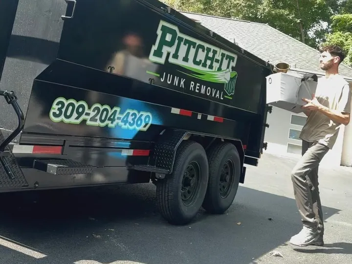 Loading a box into the Pitch It dump trailer on a driveway
